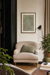 Botanics VI — Scrub. Abstract sage and olive field with coral speckle and darker green clumps near the top right. Hung on a wall in a room. Shown framed. Frames and mounts are not included.